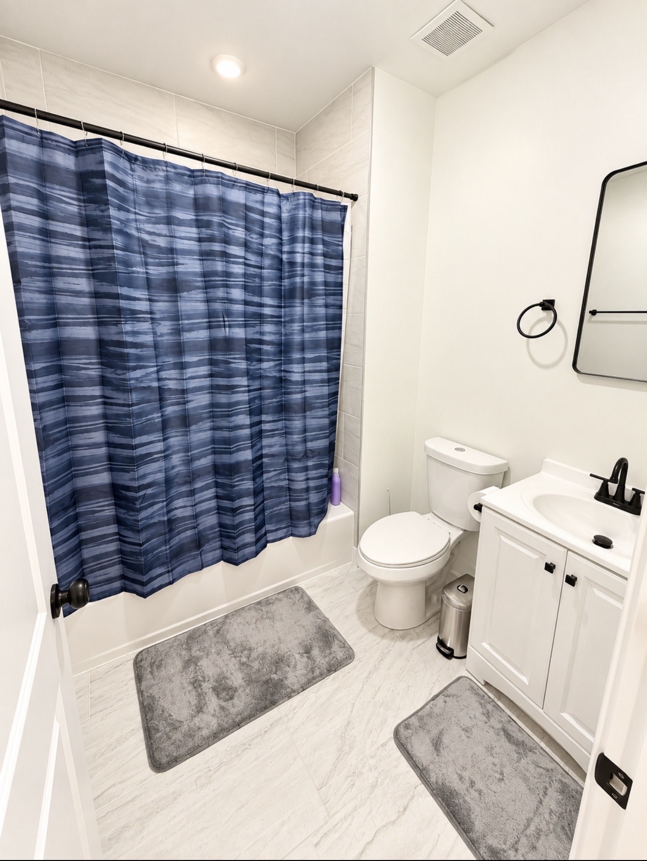 Full bathroom with vanity, framed mirror and tub with striped shower curtain