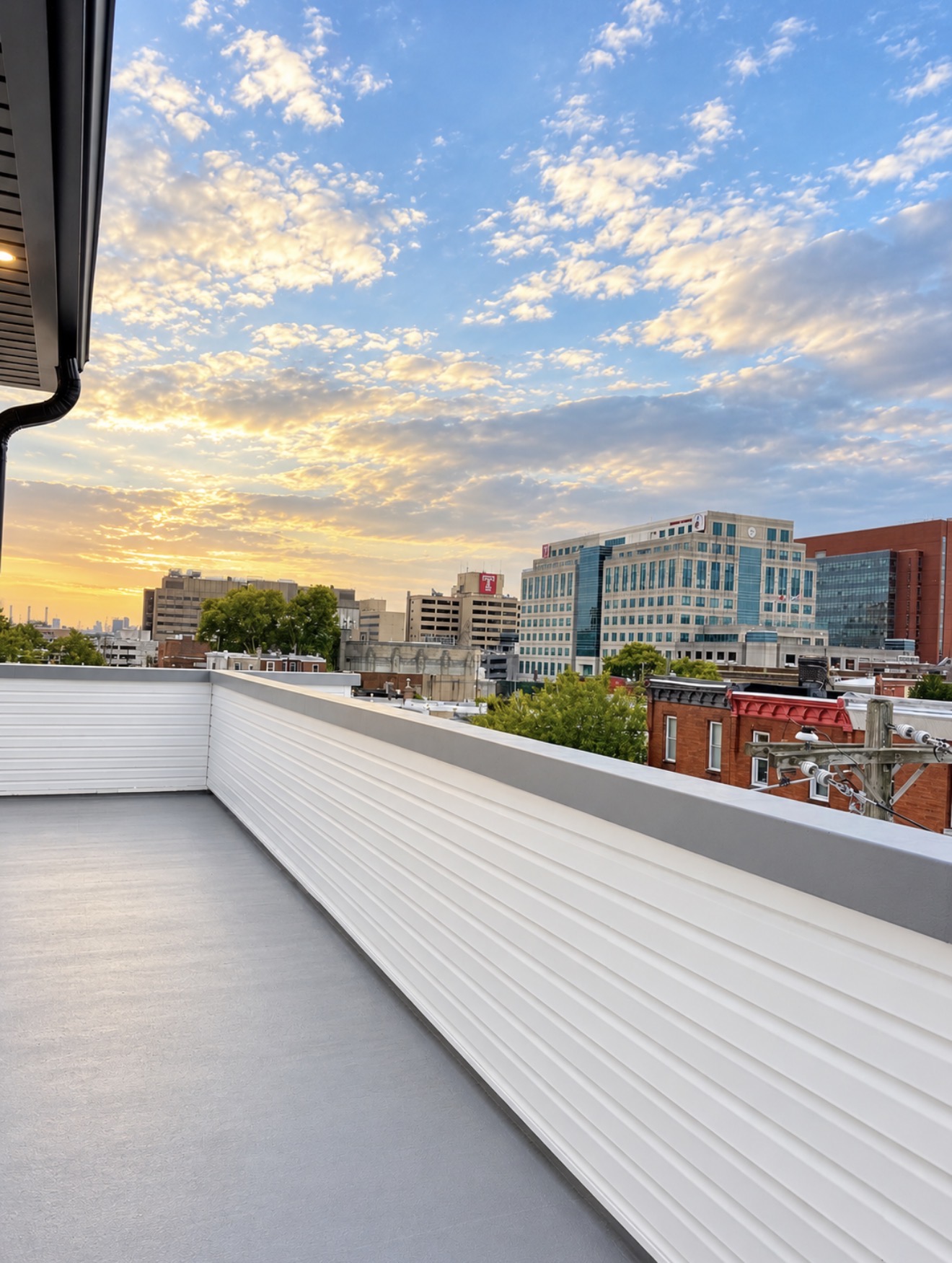 Private rooftop deck overlooking Philadelphia row houses and skyline at sunset