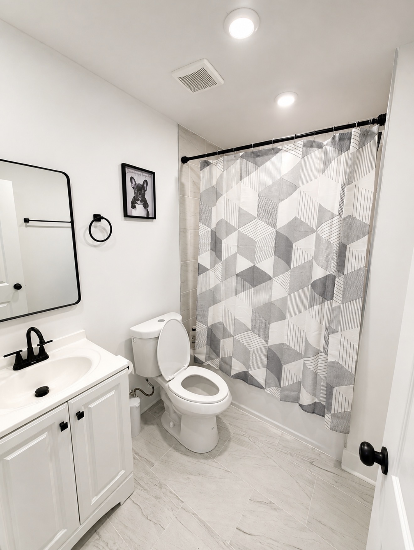 Full bathroom with white vanity, black faucet and framed French Bulldog art
