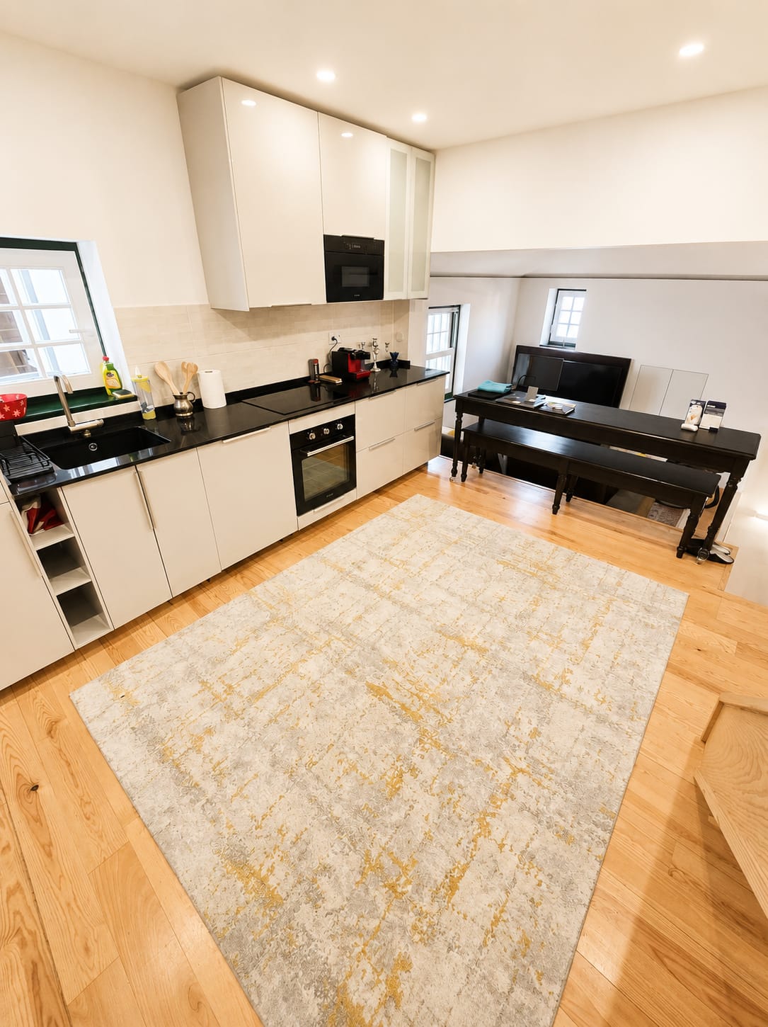 Cream galley kitchen with black granite counters, oven and a long dark dining table