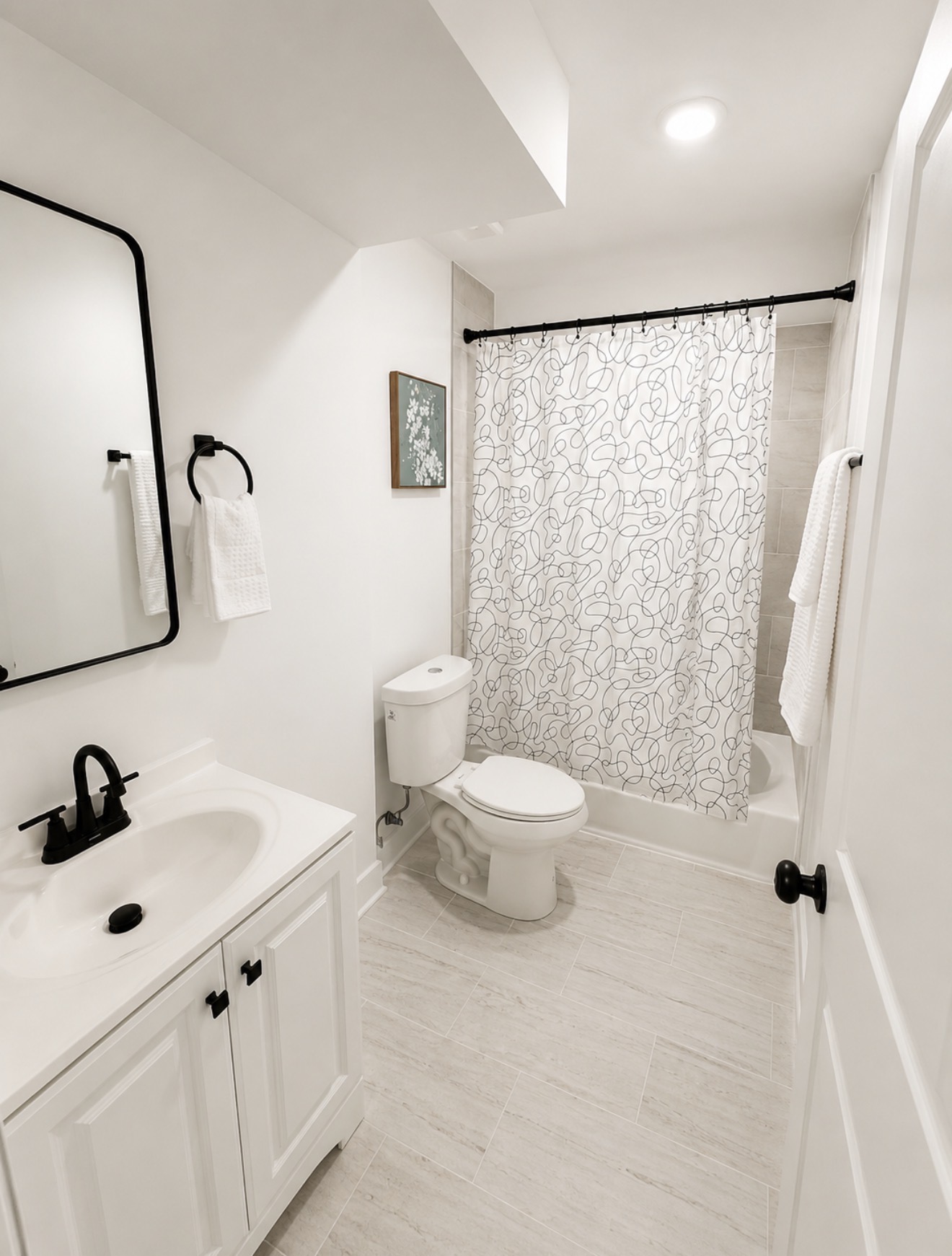 Second full bathroom with vanity, squiggle-pattern shower curtain and soaking tub
