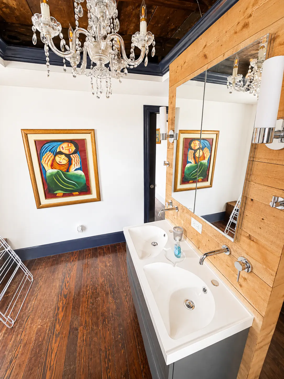 Full bathroom with double vanity, reclaimed wood wall and crystal chandelier