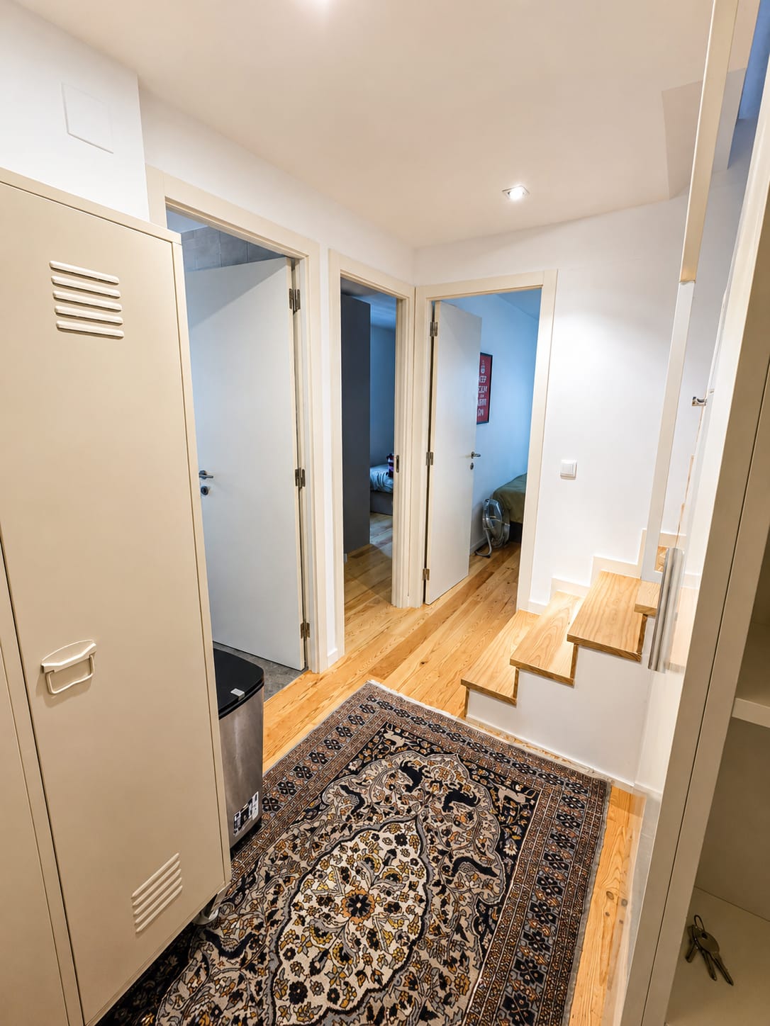 Hallway with tall storage cabinet, patterned runner and steps up to the bedrooms