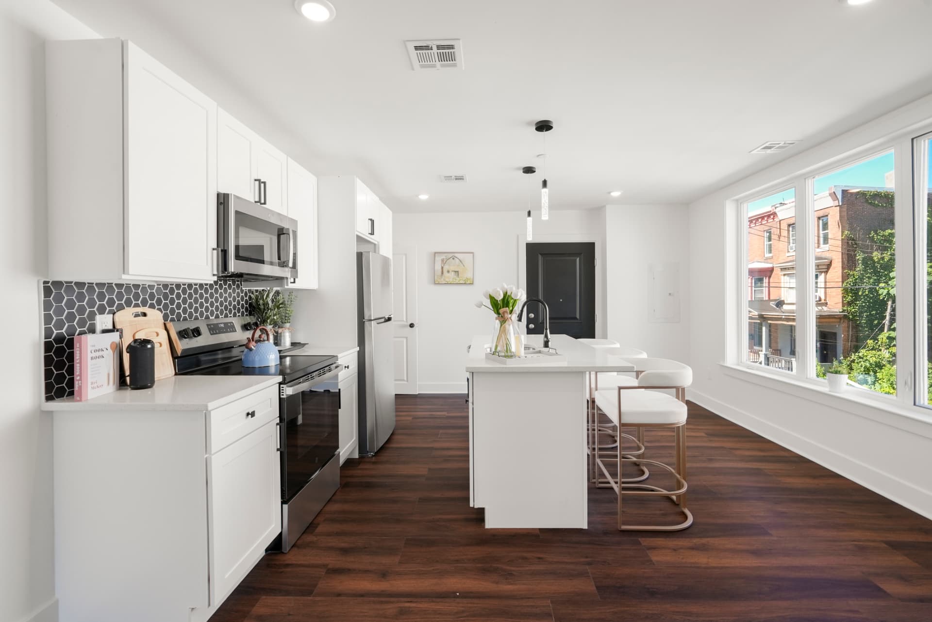 Galley kitchen with white shaker cabinets, hex tile backsplash and stainless appliances