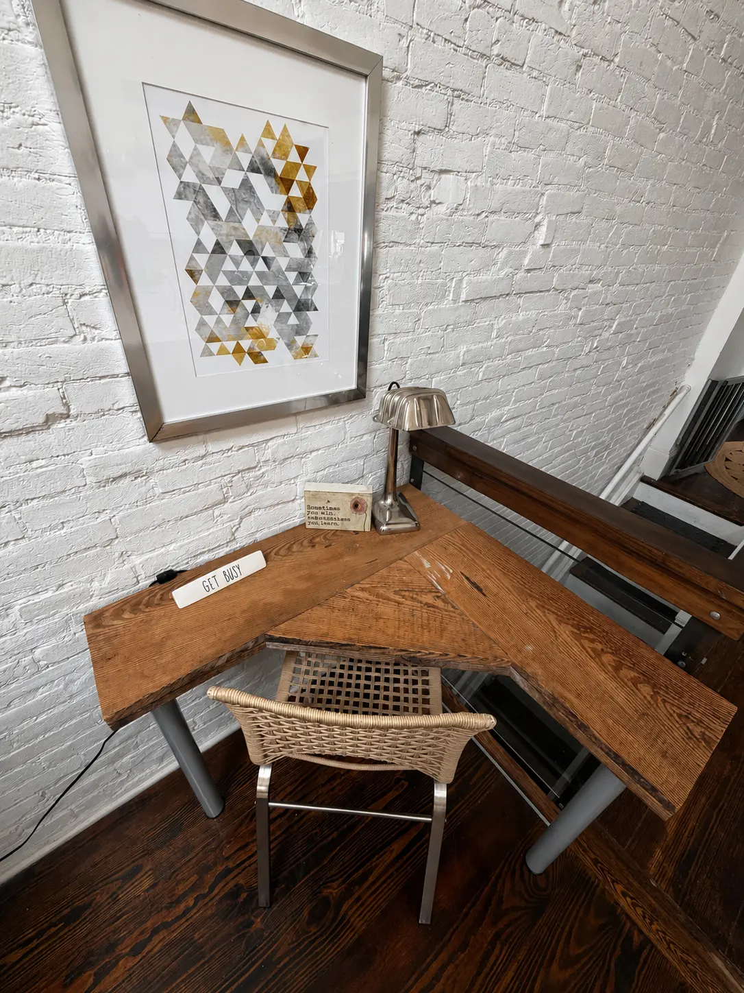 Corner workspace with reclaimed wood desk against a whitewashed brick wall