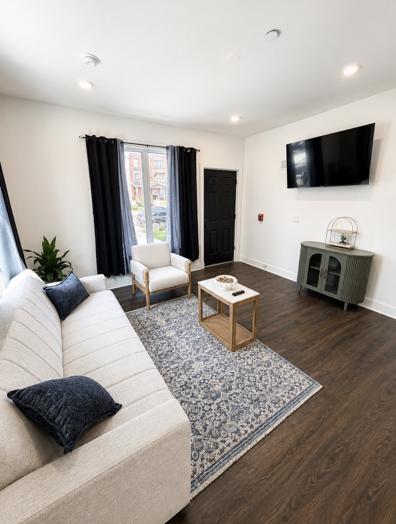Living room with cream sofa, navy pillows, wall-mounted TV and black front door
