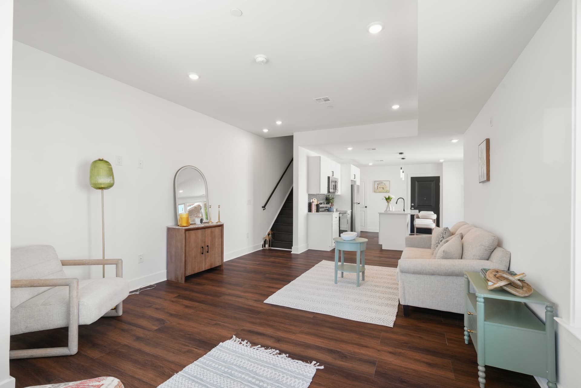 Bright bi-level living room with dark wood floors and stairs to the upper level