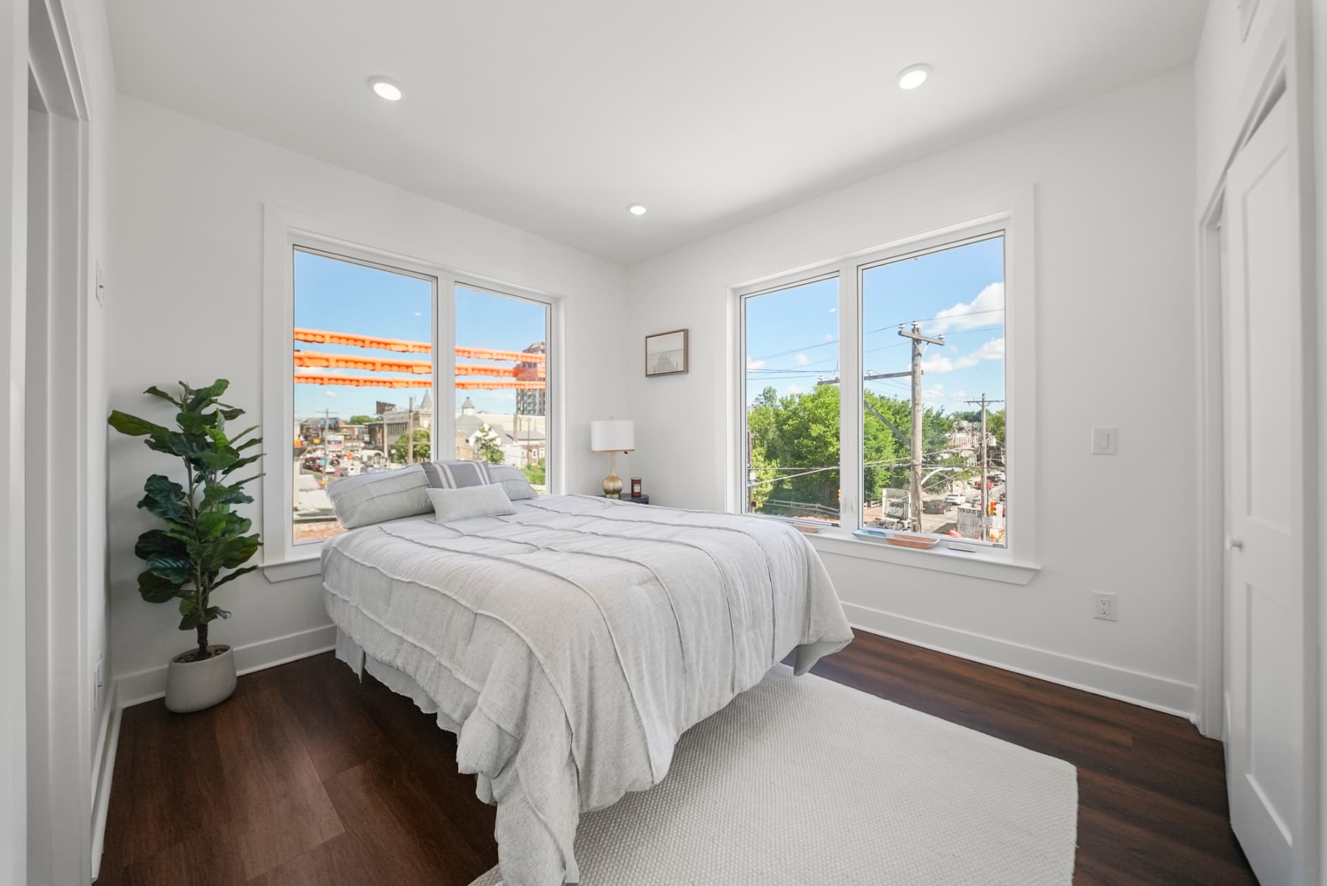 Corner bedroom with queen bed and two walls of windows with city views
