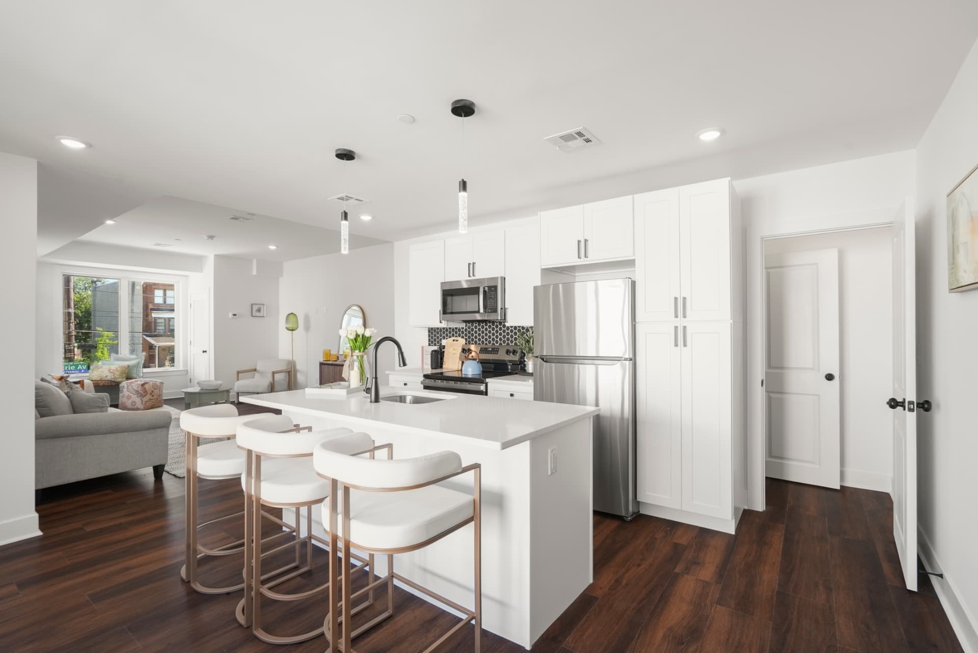 Quartz island kitchen with three bar stools opening onto the living room