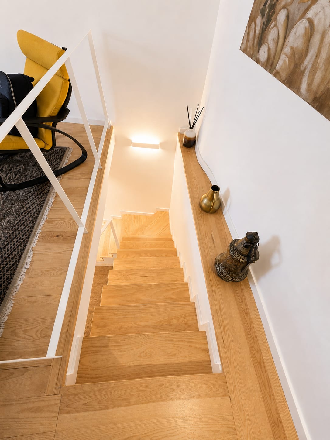 Wooden staircase with white balustrade leading down from the upper level
