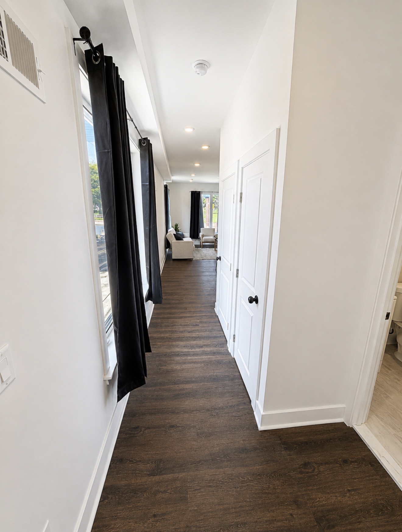 Bright hallway with large windows, white doors and dark wood floors