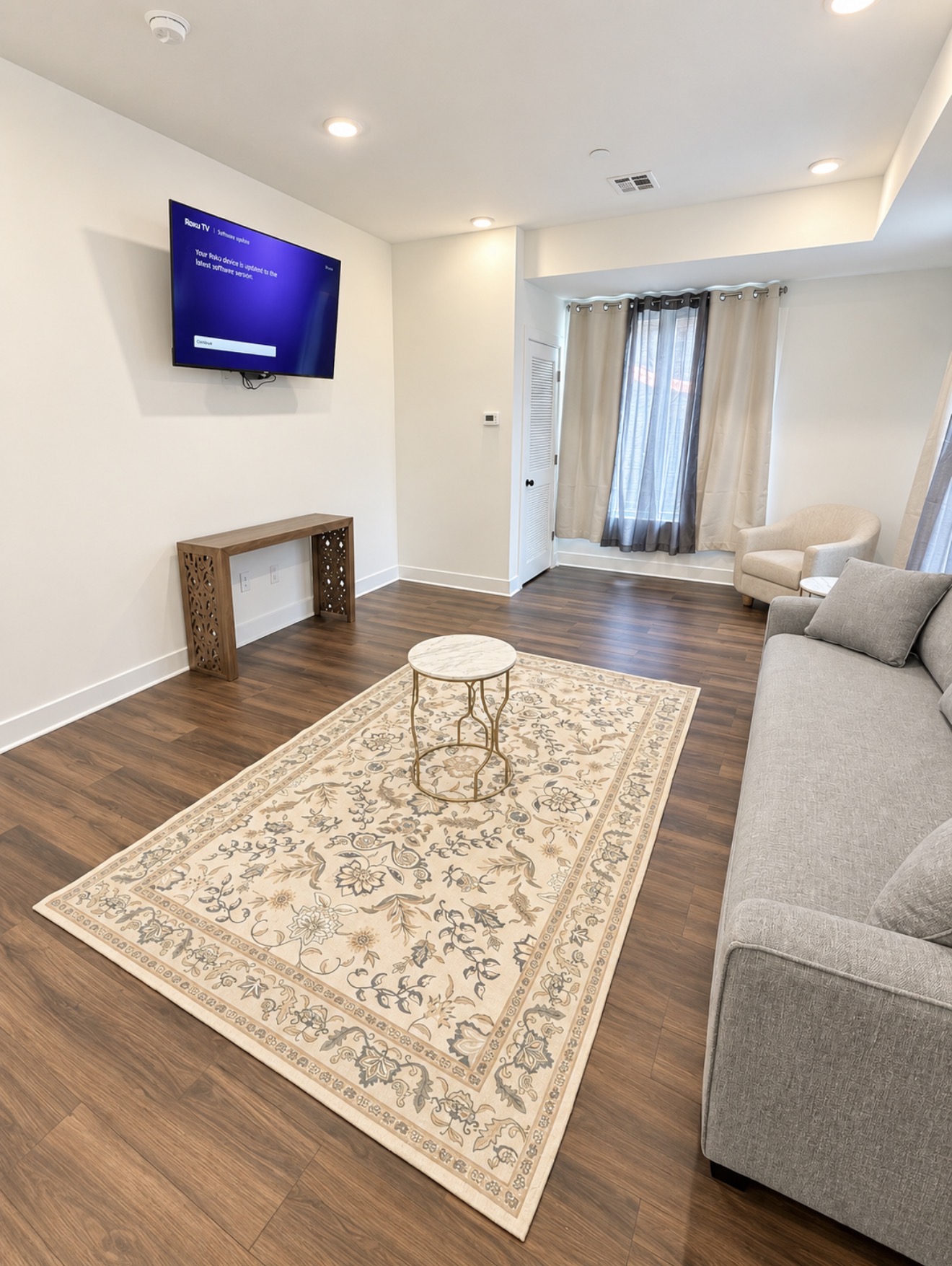 Living room with wall-mounted TV, console table and floral area rug