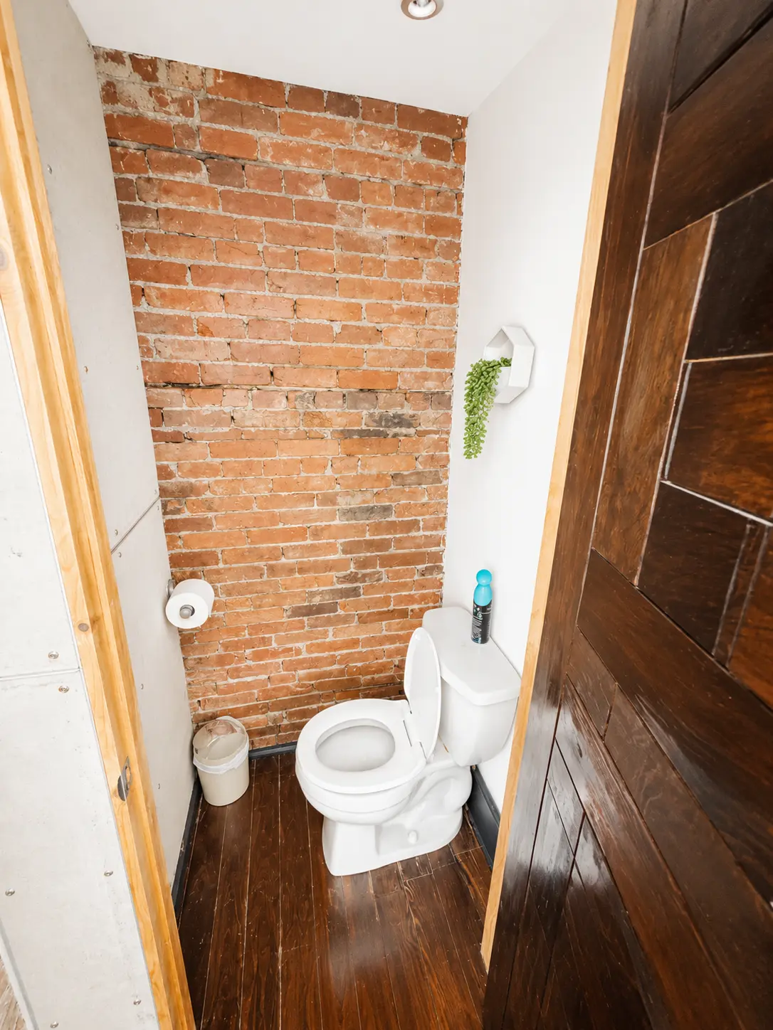 Powder room with original exposed brick wall and dark hardwood floor
